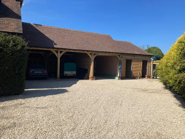 Finished three bay oak framed garage with cars parked inside